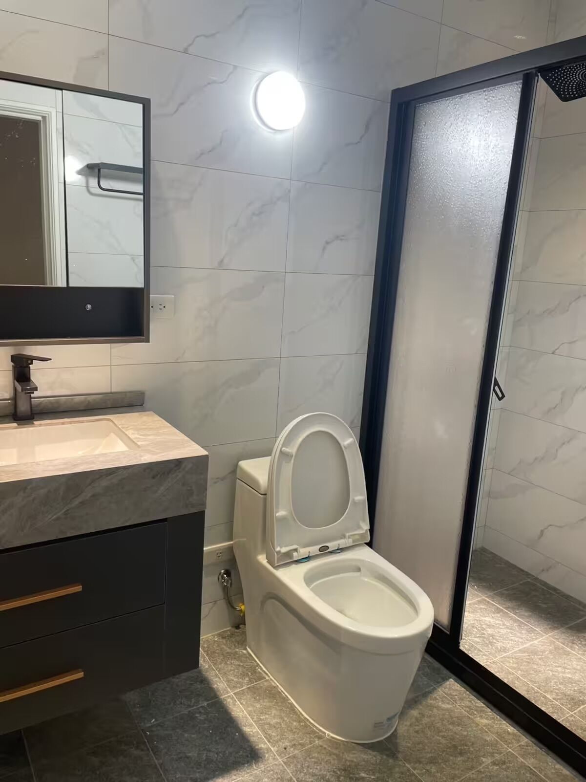 Een moderne badkamer met toilet, wastafel en spiegel.