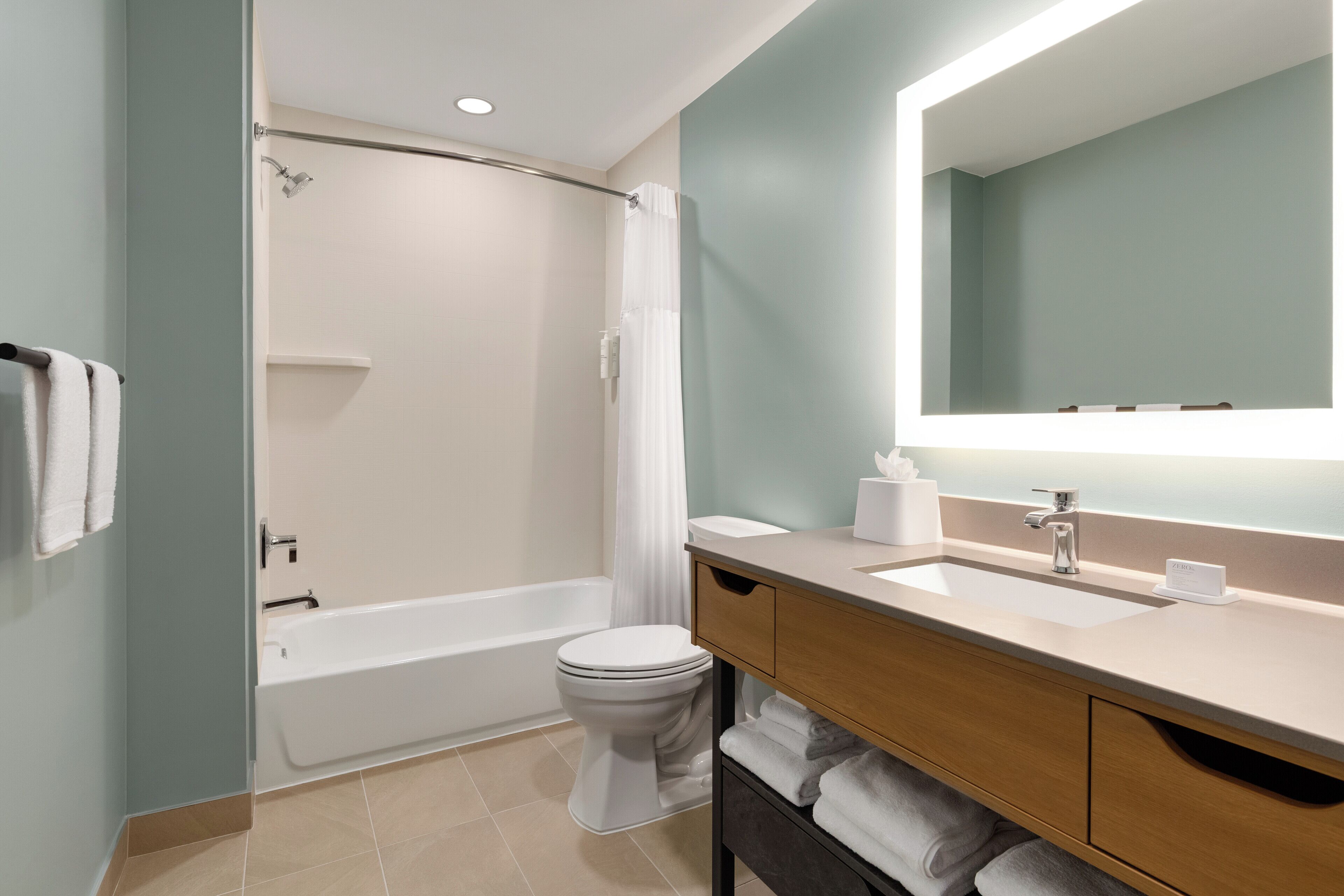 A modern bathroom with a bathtub, toilet, and vanity with a mirror.