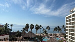 Un resort con piscina, palmeras y vista al océano.