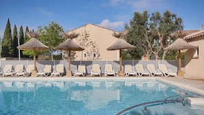 A swimming pool with lounge chairs and thatched umbrellas. - Maisonnette Confortable | Terrace Privée + Parking (Aigues Mortes)