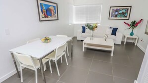 Un salon moderne avec une table à manger, des canapés blancs et une table basse.