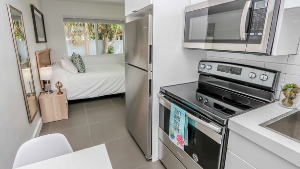 Une cuisine compacte équipée d’un réfrigérateur, d’un four à micro-ondes, d’un four traditionnel et d’un petit coin repas.