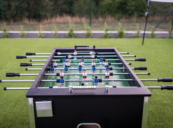Una mesa de fútbol de mesa con jugadores en uniformes azul y blanco, rodeada de un campo cubierto de césped.