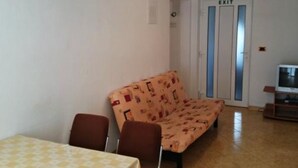 A small living area with a sofa, a table, and an exit door. - Apartments Radacic - Two Bedroom Apartment With Terrace And Sea View (A1) (Sevid)