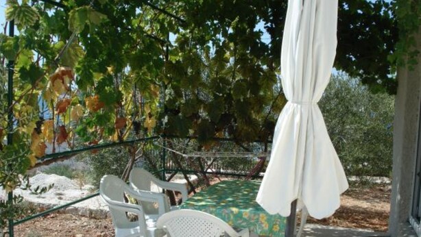 An outdoor seating area with white plastic chairs and a table covered with a green tablecloth. - Apartments Radacic - Two Bedroom Apartment With Terrace And Sea View (A1) (Sevid)
