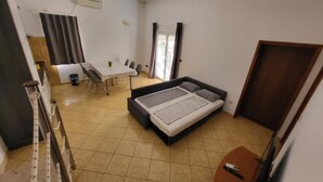 A compact room with a bed, a dining table with chairs, a small window, and a door. - Apartments Radacic - Two Bedroom Apartment With Terrace And Sea View (A2) (Sevid)