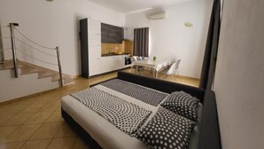 A modern room with a bed, a dining table, and a kitchen area. - Apartments Radacic - Two Bedroom Apartment With Terrace And Sea View (A2) (Sevid)