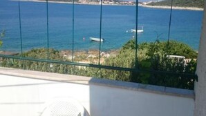 A balcony with a view of a coastal area, including a beach and a boat in the water.