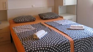 A bedroom with two beds, each with a polka dot bedspread and matching pillows. There are wooden cabinets above the beds and a small shelf.
