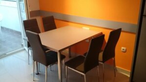 A dining area with a table and chairs, a window, and an orange wall.