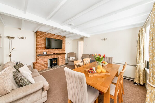 A dining area with a wooden table, chairs, and a fireplace. There is a television mounted on the wall above the fireplace. - Cottage in Thirsk With Scenic Trails & Spa (Thirsk)