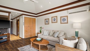 A living room with a sofa, a coffee table, a TV, and a wooden cabinet. - New Renovated April 2025 Charming Apartment In Delightful Kiahuna with AC, (Koloa)