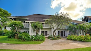 A two-story house with a balcony, surrounded by well-maintained lawns and tropical plants. - New Renovated April 2025 Charming Apartment In Delightful Kiahuna with AC, (Koloa)