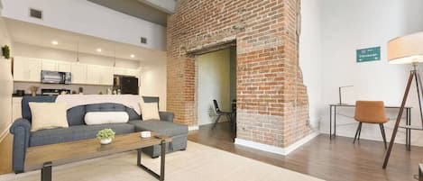 A modern living room with a sofa, coffee table, and a brick fireplace.
