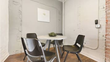 Quarto com uma mesa redonda, quatro cadeiras, uma obra de arte na parede e uma parede de tijolos.