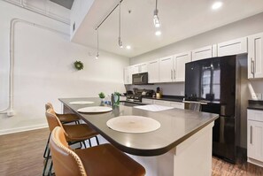 Una cocina moderna con una isla central, electrodomésticos de acero inoxidable y armarios blancos.