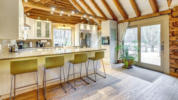 Una cocina con techo de madera, una isla grande con taburetes de bar y vistas al exterior.