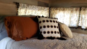Una cama con un edredón blanco, un almohadón marrón y un almohadón con lunares.