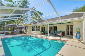 Ein überdachter Swimmingpool mit Terrassenbereich, Stühlen und Deckenventilator.
