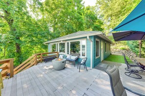 A covered deck with outdoor seating, a fire pit, and a view of a lush garden. - Fish, Swim & Explore: Mukwonago Lake House! (Mukwonago)