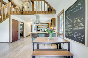 A modern kitchen with a wooden staircase, a dining table with a vase of flowers, and a chalkboard with house rules and favorite hikes. - Steps to Crystal River: Hideaway w/ Mountain Views (Marble)