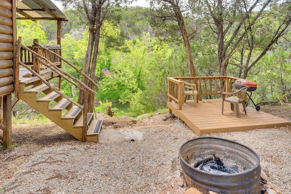 A wooden deck with a fire pit, outdoor seating, and a staircase leading to a cabin. - Cedar Falls Cabin 2: Family Getaway By Honey Creek (Davis)