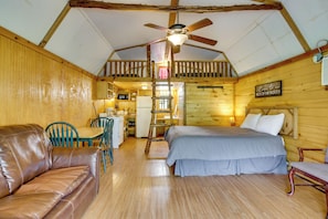 Interior de cabana com quarto em mezzanine, área de jantar e cozinha compacta.