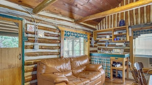 Ein Blockhaus-Interieur mit Ledersofa, Holzregalen und einem Check-out-Schild.