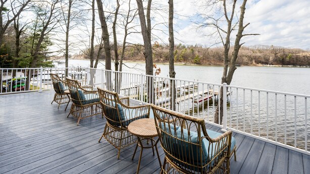 A wooden deck with wicker furniture and a view of a lake.