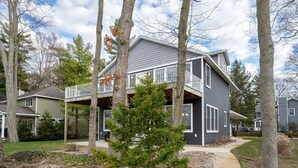 A two-story house with a balcony, surrounded by trees and a grassy yard.