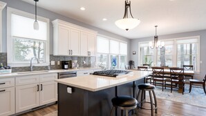 A modern kitchen with white cabinets, a large island, and bar stools.