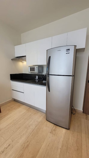 Enjoy cooking in this well-equipped kitchen with a refrigerator, microwave, and range hood.