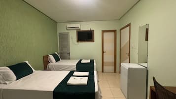 A hotel room with two beds, a TV, a refrigerator, and a door.