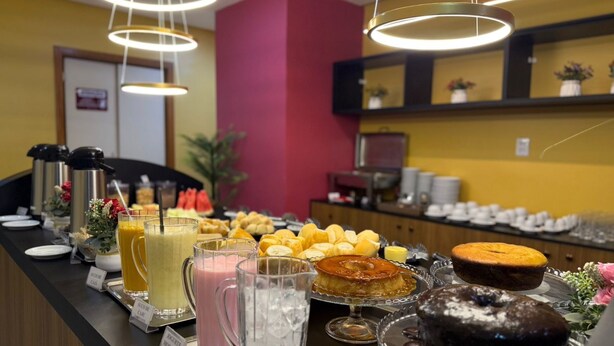 A buffet with various food items and beverages, including a chocolate cake, a fruit display, and a coffee station.