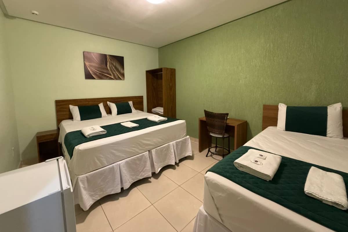 A hotel room with two beds, a desk, a chair, and a wardrobe.