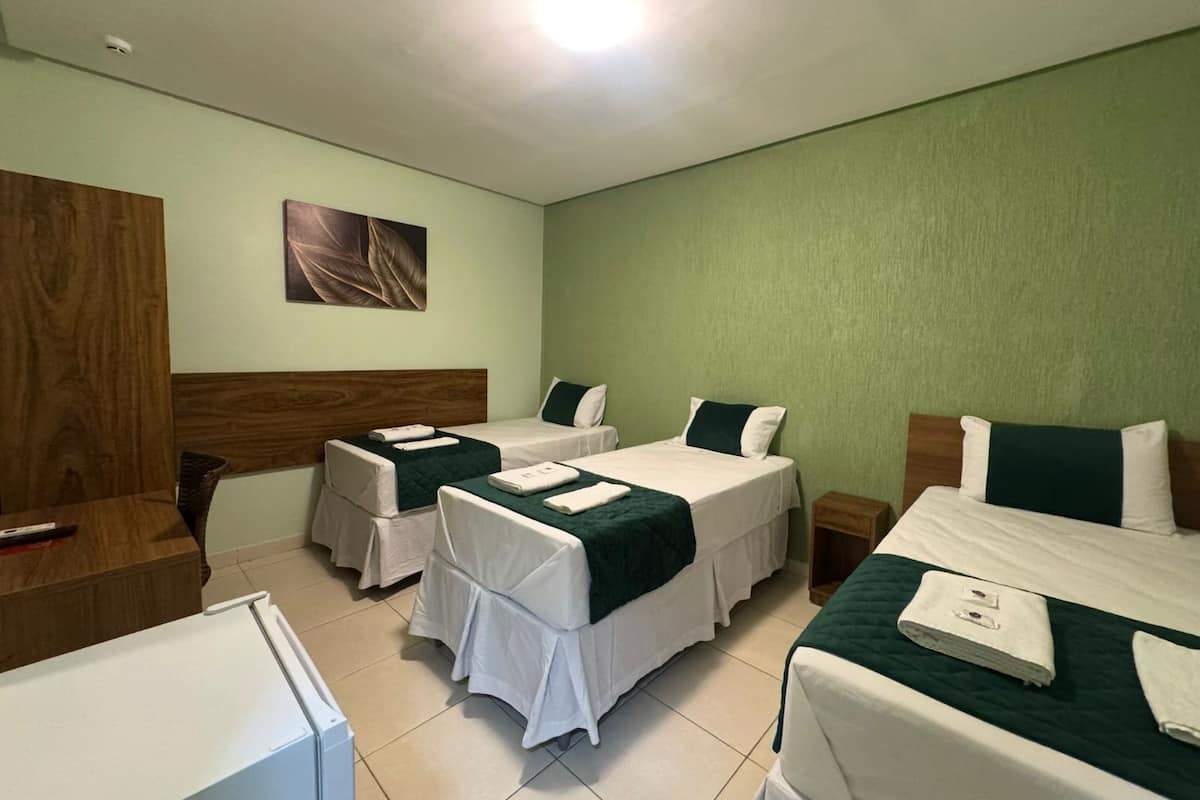 A hotel room with two single beds, a wooden headboard, a small table, and a wall-mounted artwork.