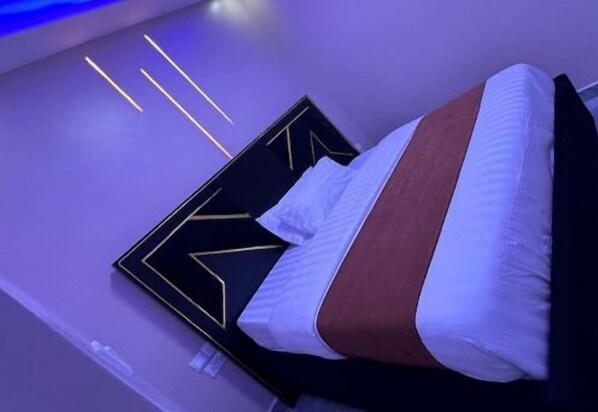 Relax in a stylish bedroom with a geometric-patterned headboard and a comfortable bed.