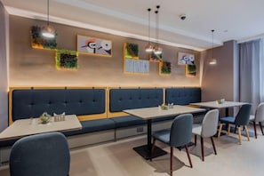 A modern dining area with a long bench seating, tables, and chairs.