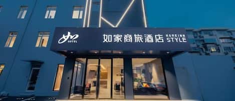 A hotel entrance with a modern design, featuring a prominent logo and signage.