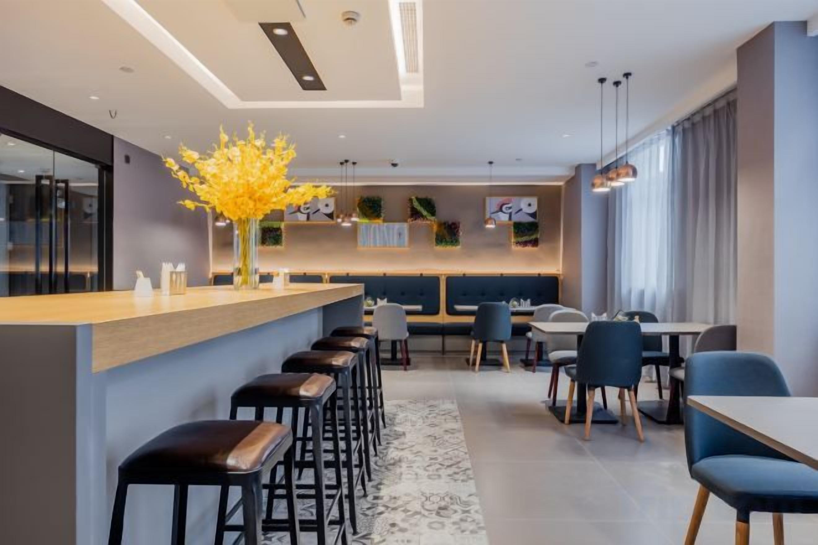 A modern dining area with a bar, high stools, and a central seating arrangement.