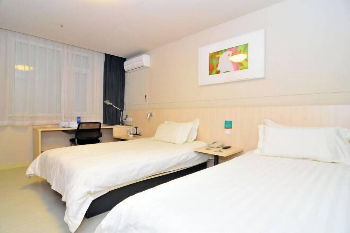 Habitació d'hotel amb dos llits, un escriptori, una cadira, una làmpada i un quadre a la paret.