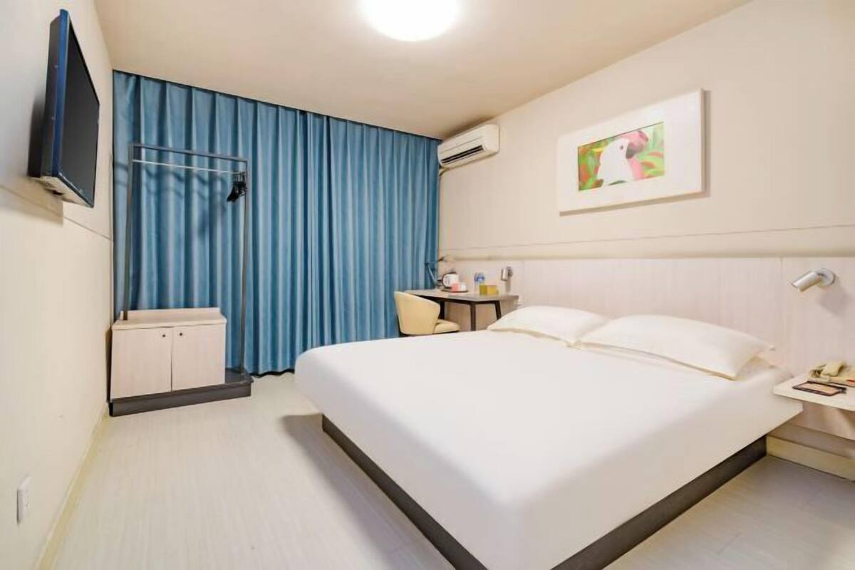 Una habitació d'hotel amb un llit, escriptori, cadira, televisió i un quadre a la paret.