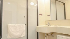A bathroom with a white sink, a mirror, and a towel hanging on the wall.