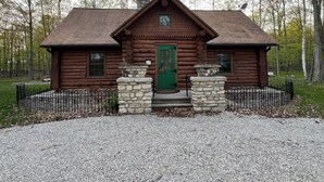 A log cabin with a green door, two windows, and a stone base. - Gibby's Log Cabin Retreat (Washington)