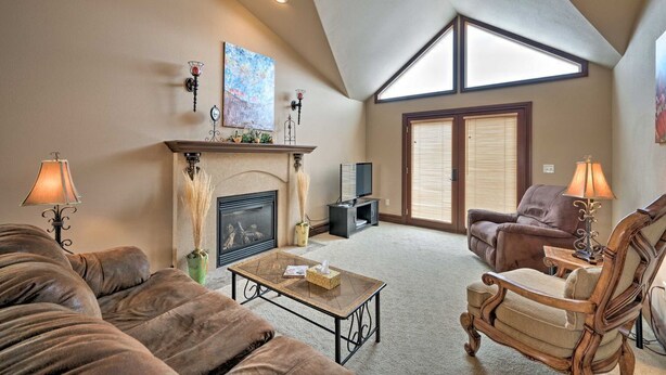 A spacious living room with a fireplace, a large window, and a high ceiling. -  Cozy Fairway Retreat - Near Ski, Golf & Town (Red Lodge)