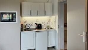 A compact kitchen with white cabinets, a microwave, a clock, and a sink. - New cocoon between sea and countryside 4Pers Private parking (Villers-sur-Mer)