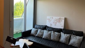 A modern living room with a black leather sofa, a wooden coffee table, and a world map artwork on the wall. - New cocoon between sea and countryside 4Pers Private parking (Villers-sur-Mer)