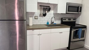 Una cocina moderna con electrodomésticos de acero inoxidable, armarios blancos y salpicadero de azulejos.