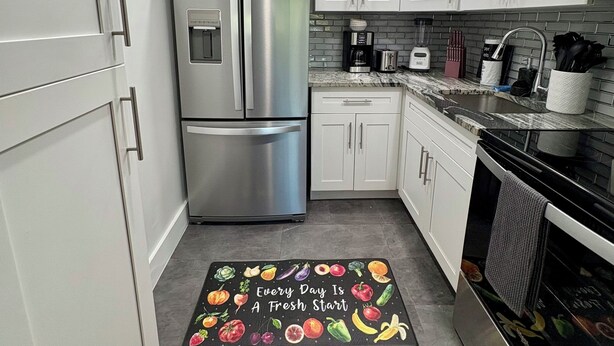 A modern kitchen with white cabinets, stainless steel appliances, and a black and white patterned rug. - Stylish 1-bed apartment, in East Delray Beach, pets, parking, free laundry (Delray Beach)