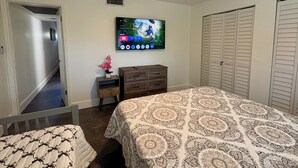 A bedroom with a bed, a dresser, a TV mounted on the wall, and a closet. - Stylish 1-bed apartment, in East Delray Beach, pets, parking, free laundry (Delray Beach)